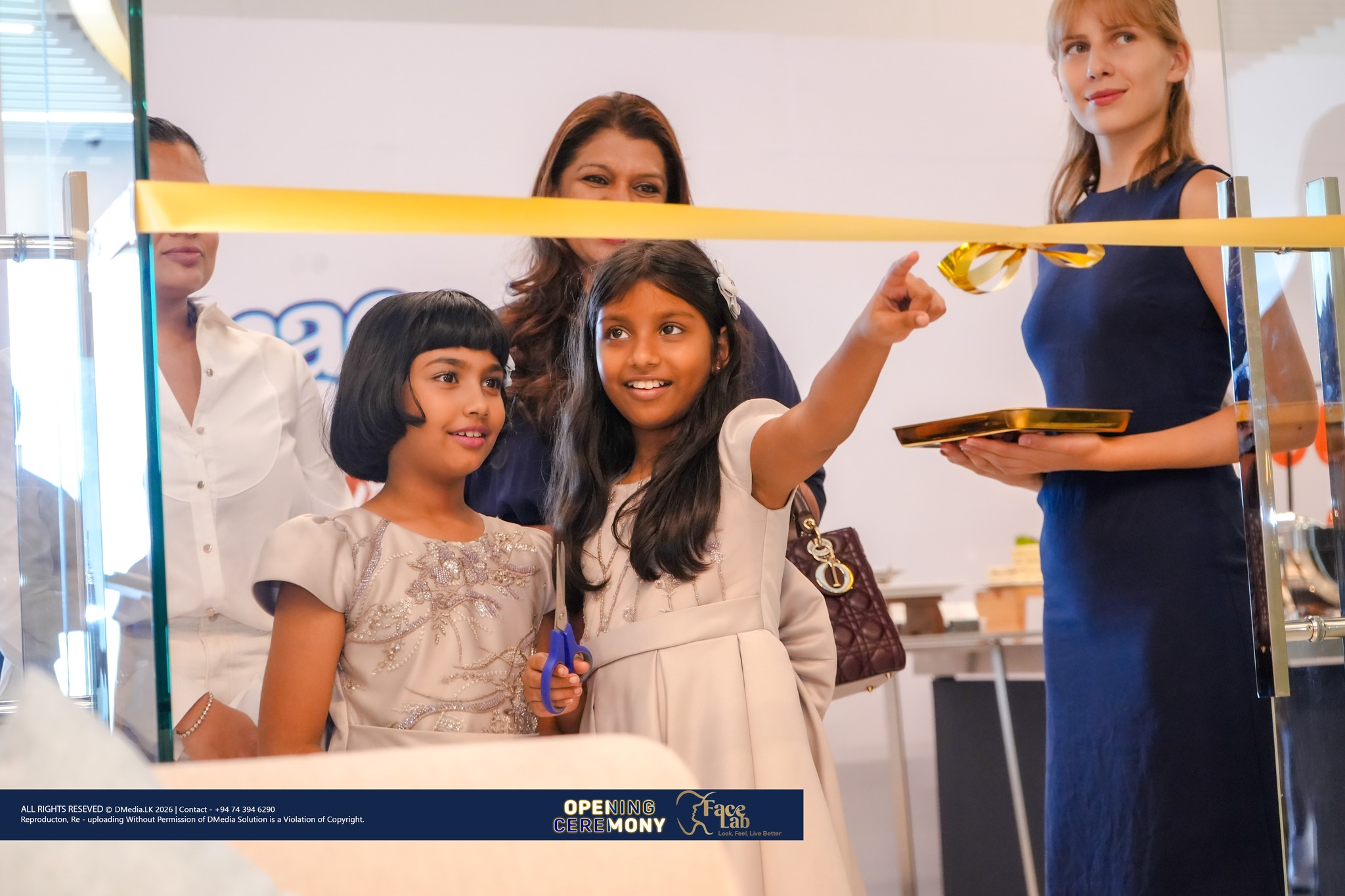 Two young guests hold the scissors and ribbon at the FaceLab opening